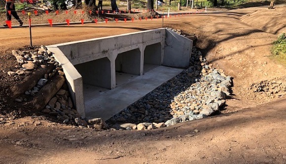 Image Three concrete box culverts support the gravel road above 