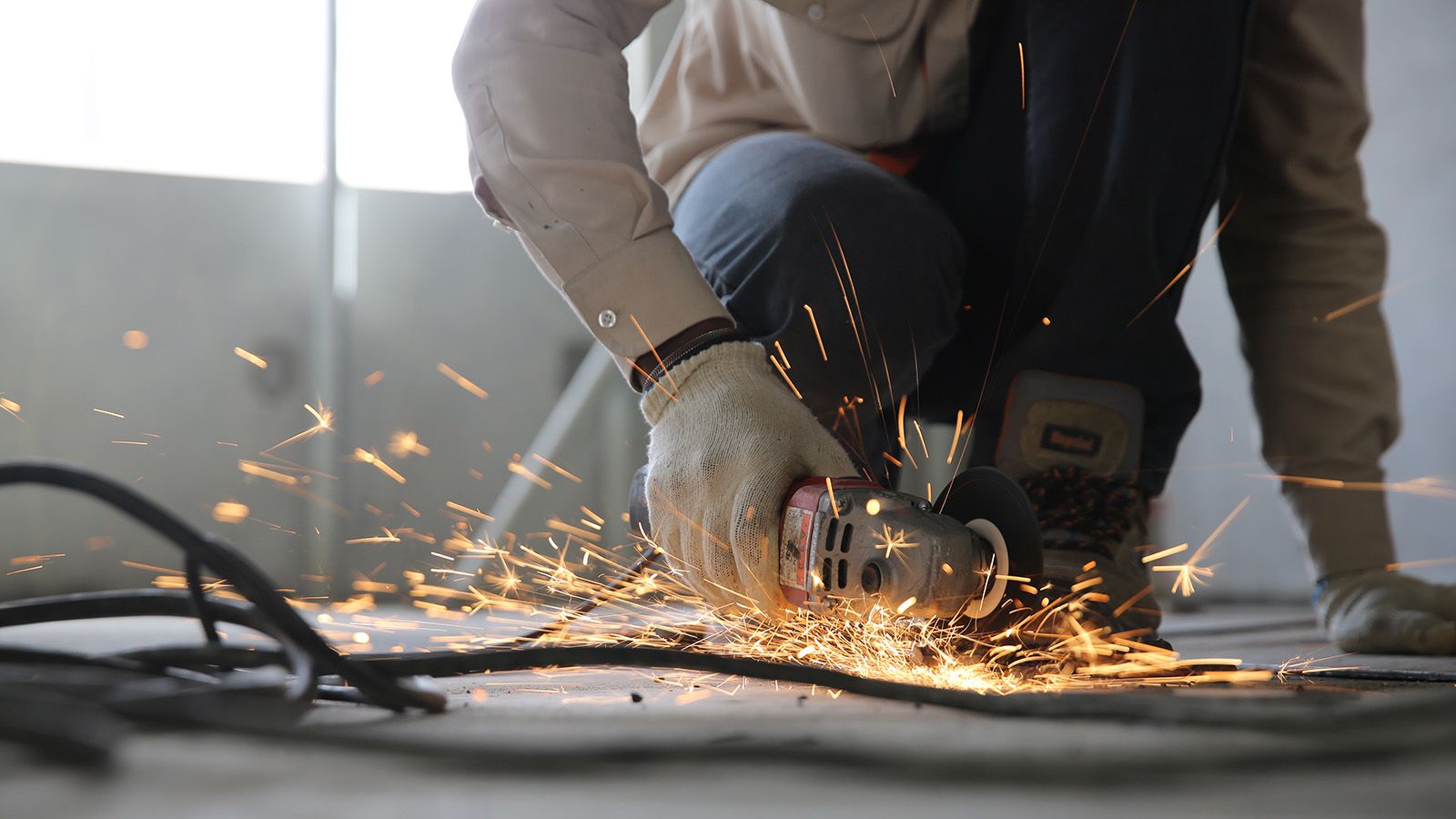 A man using a grinder powertool, creating sparks banner image