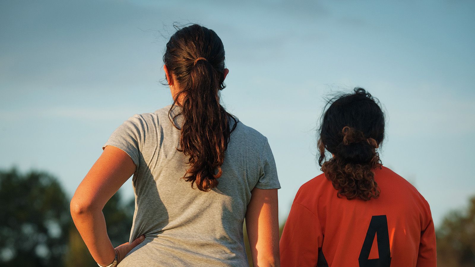 The backs of two women wearing different sporting uniforms banner image