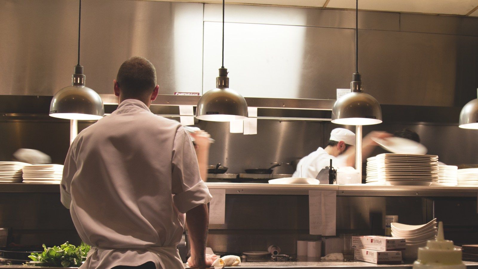 Chef in restaurant kitchen preparing food with another chef in the background banner image