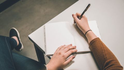 Woman sitting with pen on open notebook