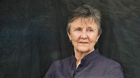 Wrinkly lady with short hair in front of black background