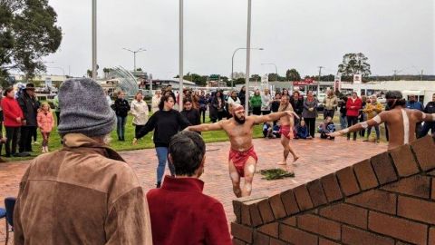 Aboriginal dancers in front of a crowd on a cloudy day