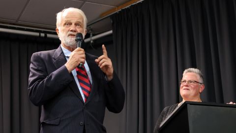 Man with a microphone with a lady standing behind him