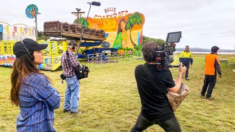 Woman watches man filming carnival setup