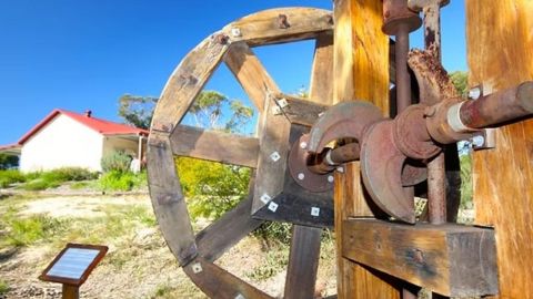 Photo of a historic wooden wheel used to bring gold up from a mine.