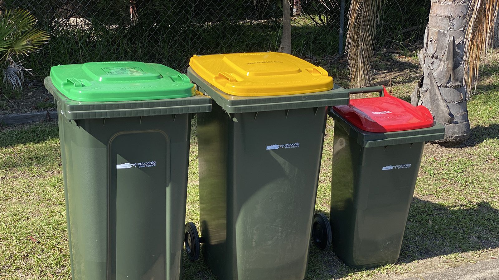 Three household bins, with a gree, yellow, and red lid. banner image