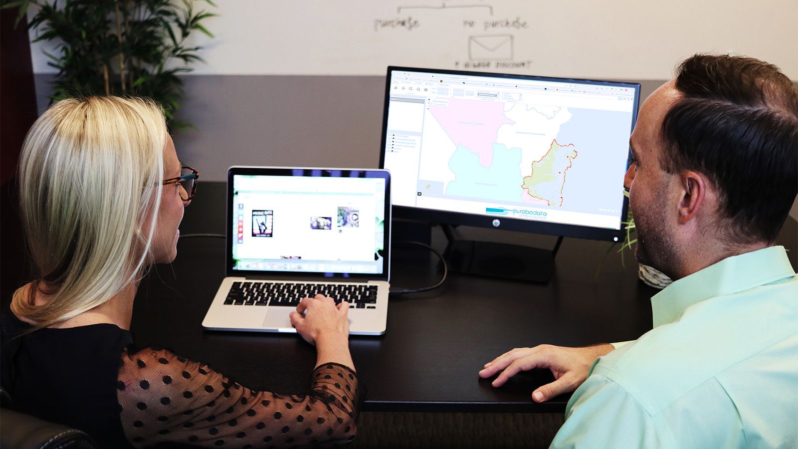 A person instructing another person to use a computer program at an office. banner image