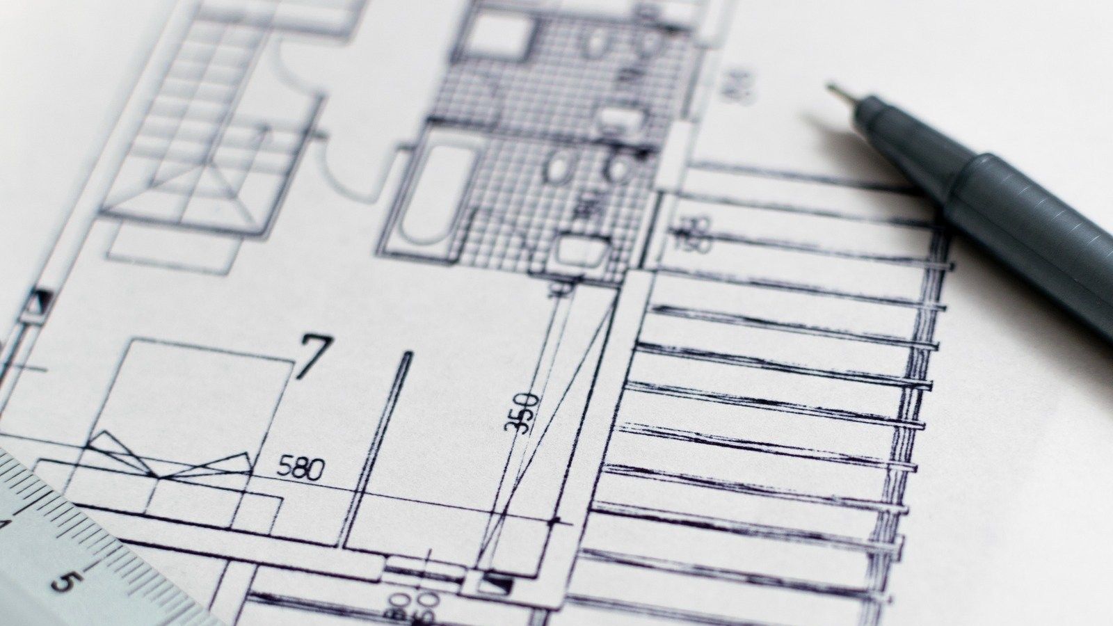 Building plans with black pen laying across them banner image