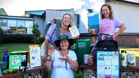 Three young women in front of building surrounded by sustainability paraphanalia