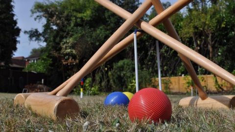 Croquet balls and mallets on a grass surface.