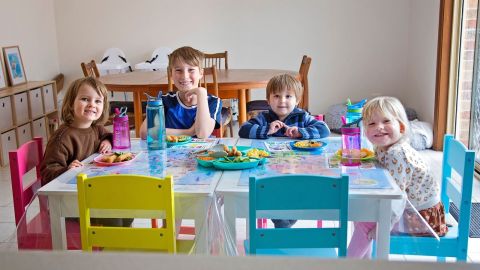 Four children seated around a table with lunch foods.