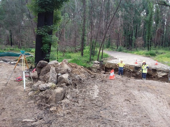 Image Workmen stand in a gaping hole in the road 