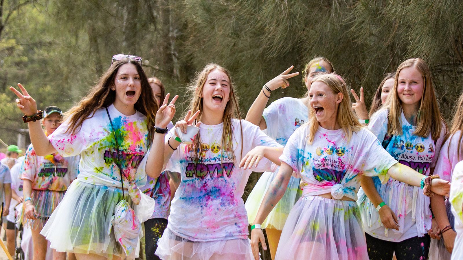 Four teenage girls in colourful pastel clothing singing together banner image