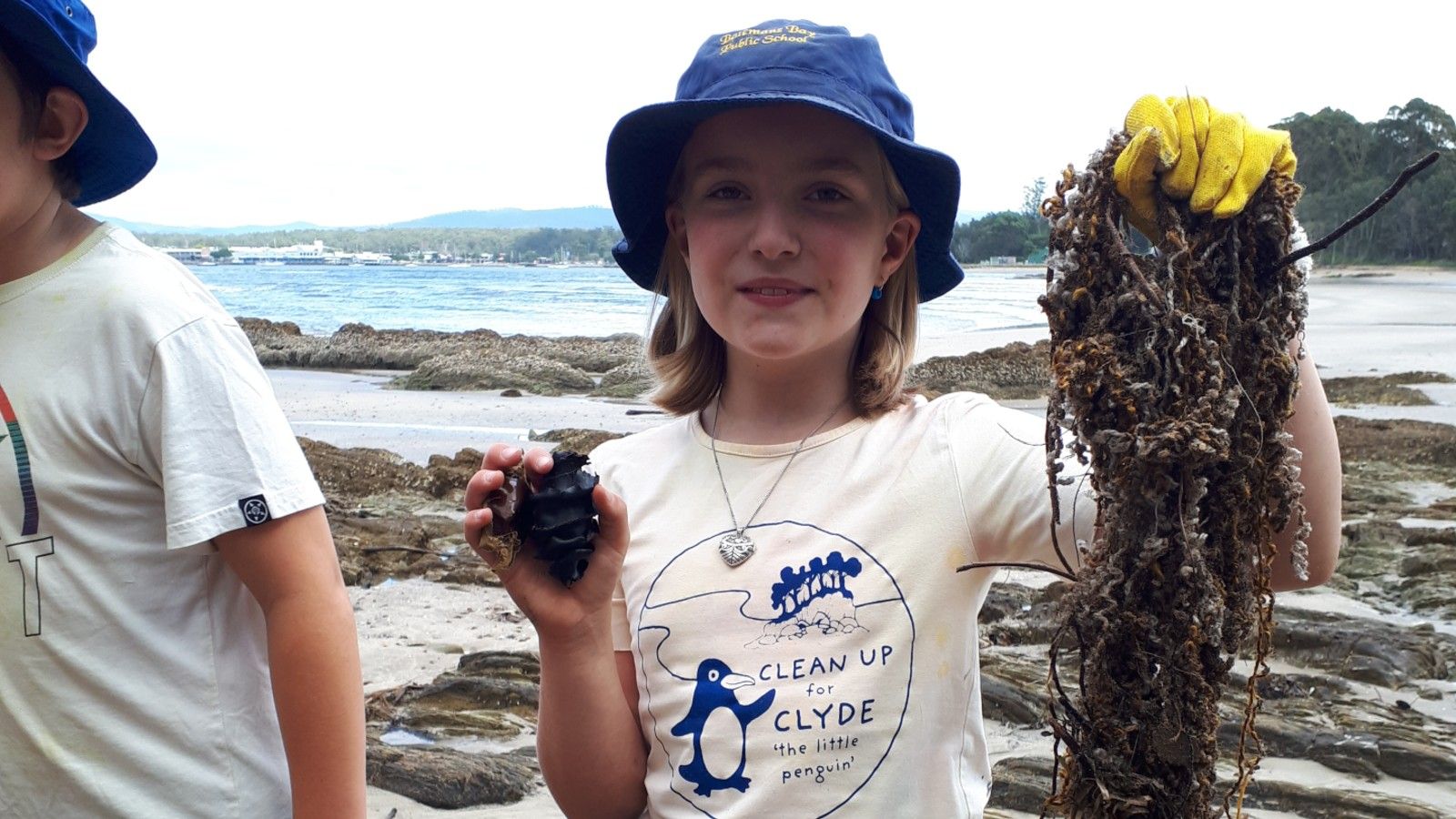 A young girl wearing a blue hat holding onto some marine debris banner image