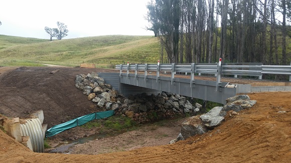 Image A bridge under construction sits above a narrow stream of water