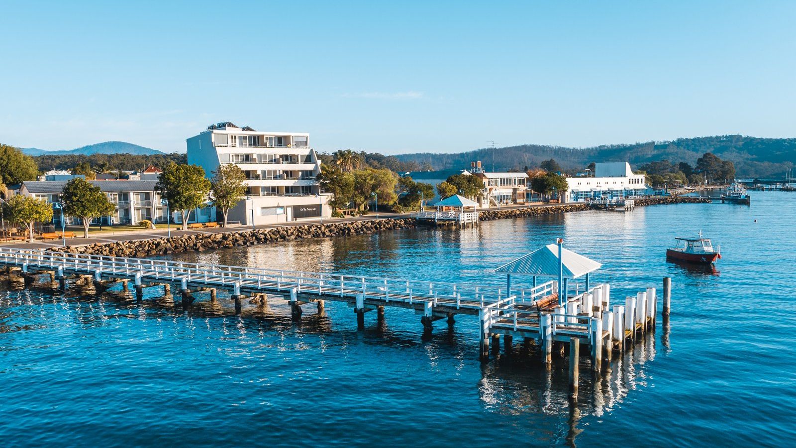 Batemans Bay waterfront with shops and jetty alongside the water banner image