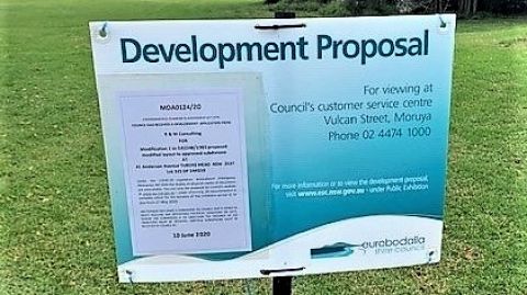 Official sign in front of undeveloped grassy paddock