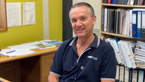 Man in blue shirt sitting behind desk