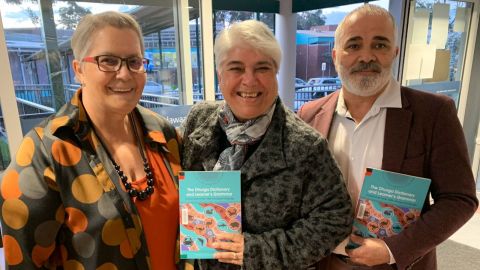 Three people standing with a book