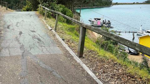 Damaged bitumen footpath along scenic inlet