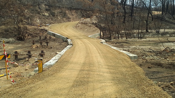 Image Concrete barriers contain a temporary road built across the dry creek bed