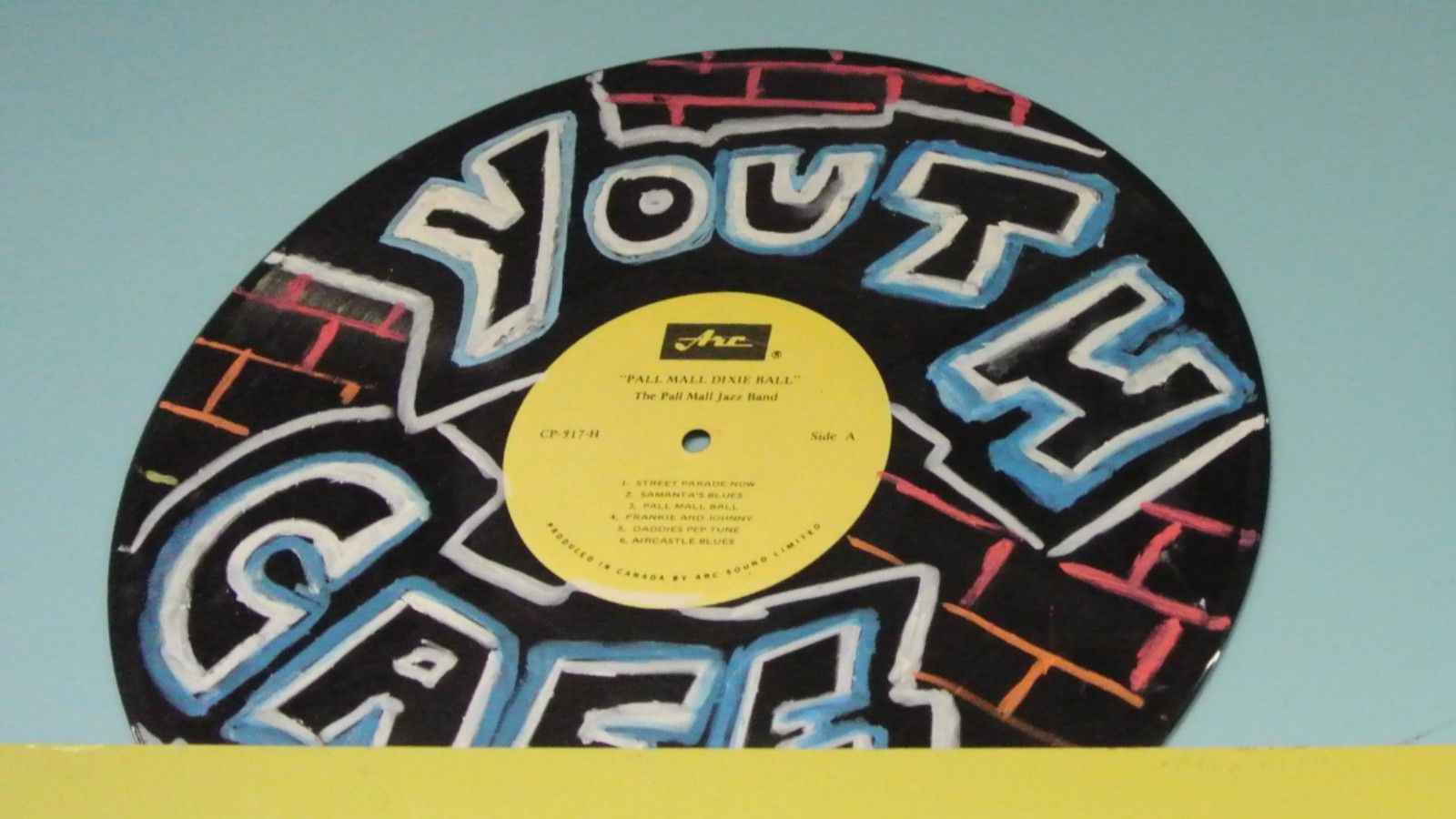An LP record with youth cafe painted on it. banner image