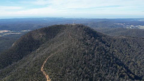 Aerial view of a mountain with a telecommunications tower on top.
