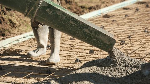 Machine pouring wet concrete on to path reo