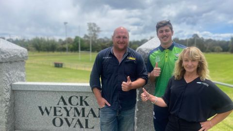 Three people standing in front of an oval 