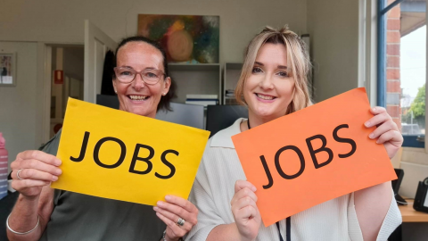 Two females holding signs that say jobs