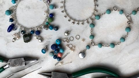 Assorted beading tools and three completed bracelets.