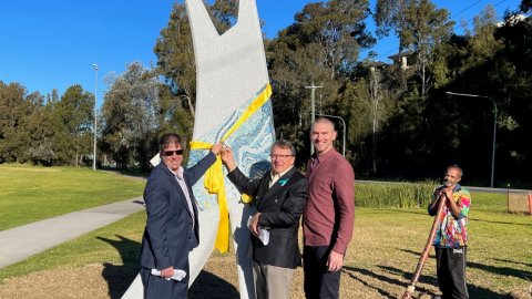 Three people standing in front of a sculpture 