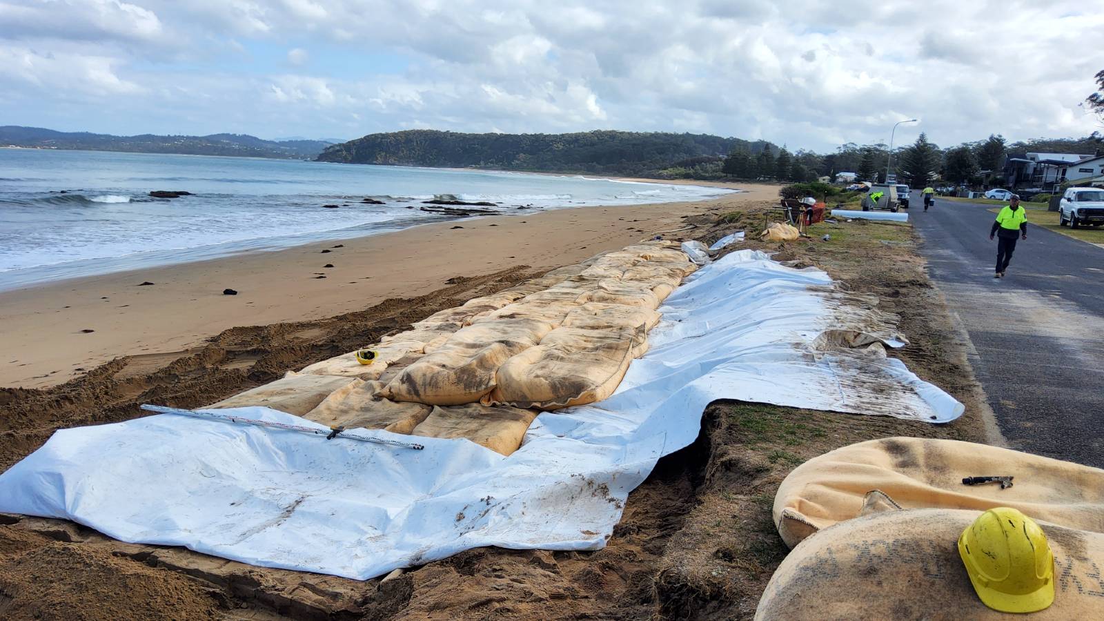Image Large sandbags are arranged in rows along a beach on top of geofabric.