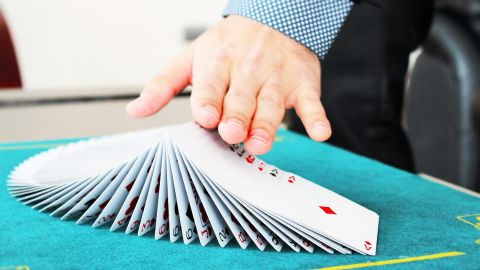 Image of a hand spreading out a pack of cards on a table for a magic trick