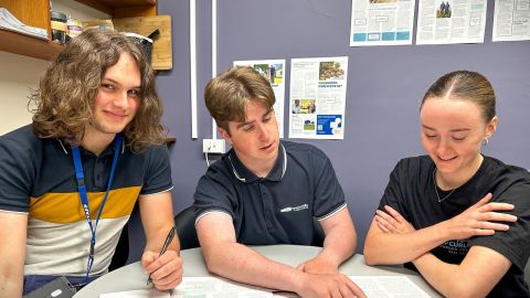 Three young people sitting at a desk