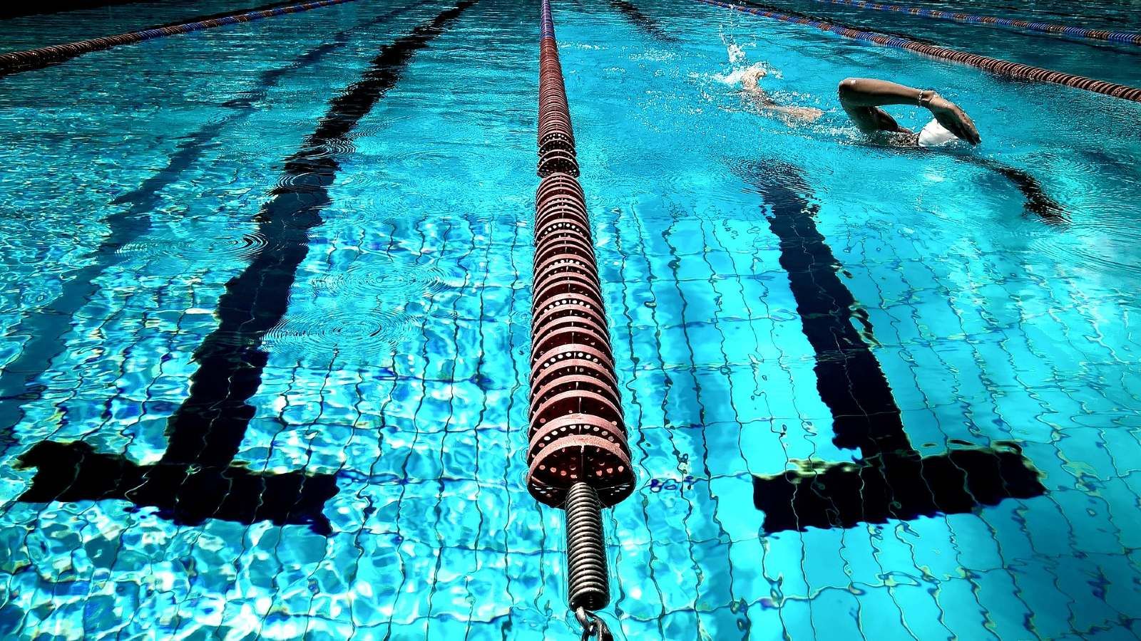 Close up image of a public swimming pool and swimmer swimming in a pool lane banner image