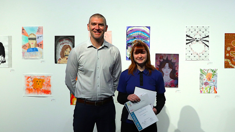 tall man next to teenage girl holding a certificate
