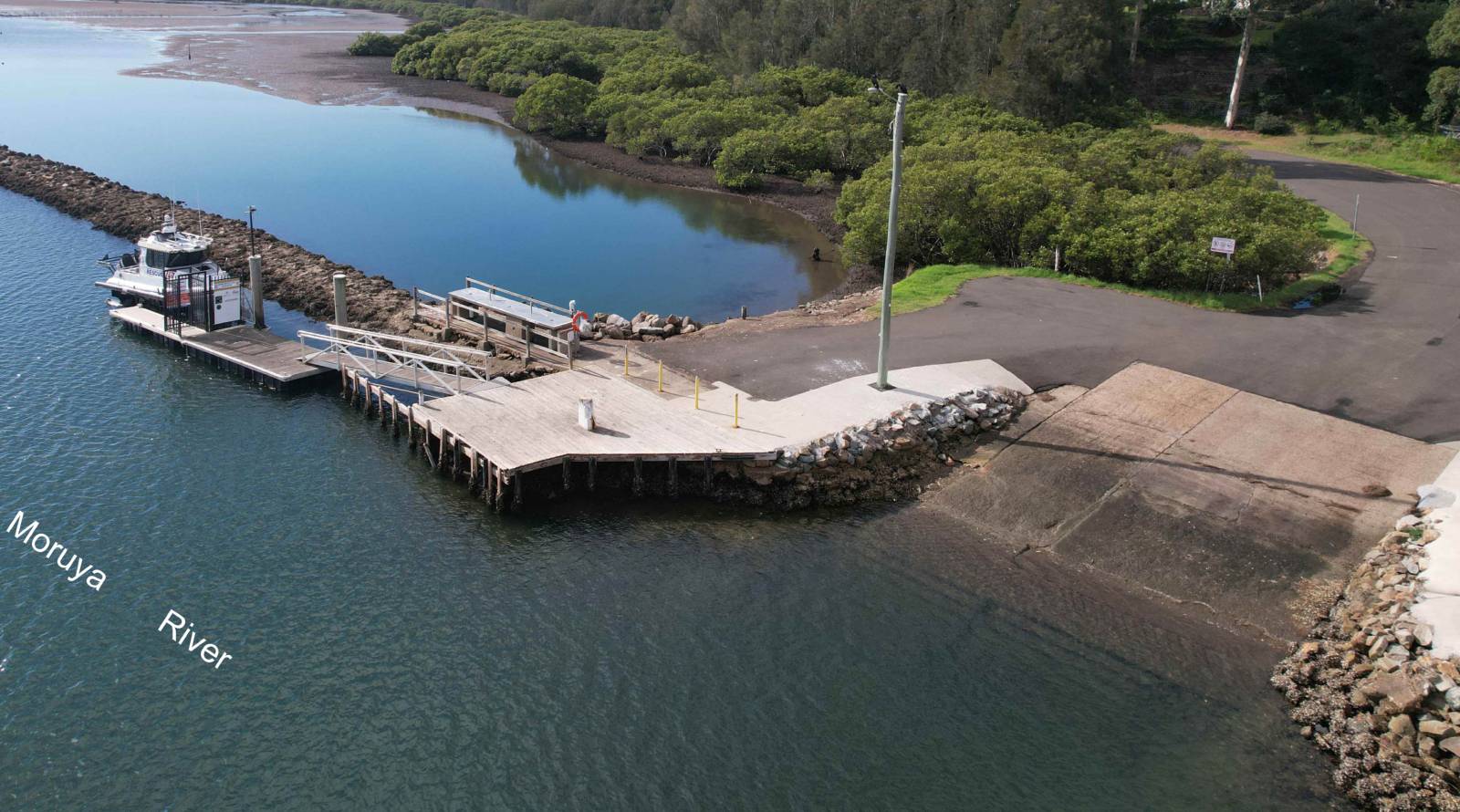Image An aerial image shows an old boat ramp alongside a timber wharf on the edge of a river.