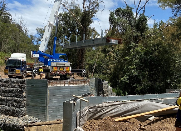 Image A crane lowers a section of new bridge deck into place