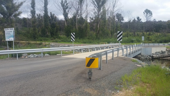 Image Road signs and guard rail guide motorists across a concrete bridge.