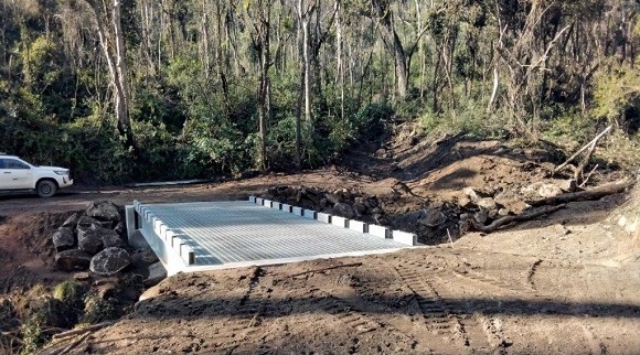 Image A short concrete bridge sits in a bushland setting on a dirt road.