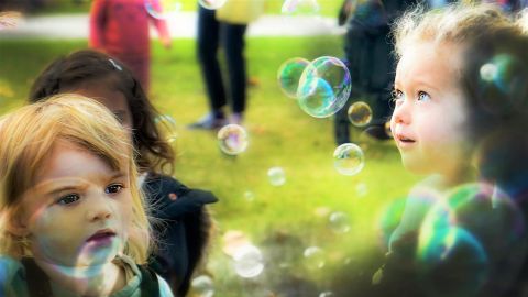 Two children blowing bubbles in a park
