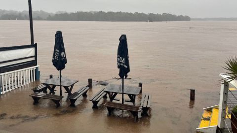 Tables and chairs inundated by brown flood waters