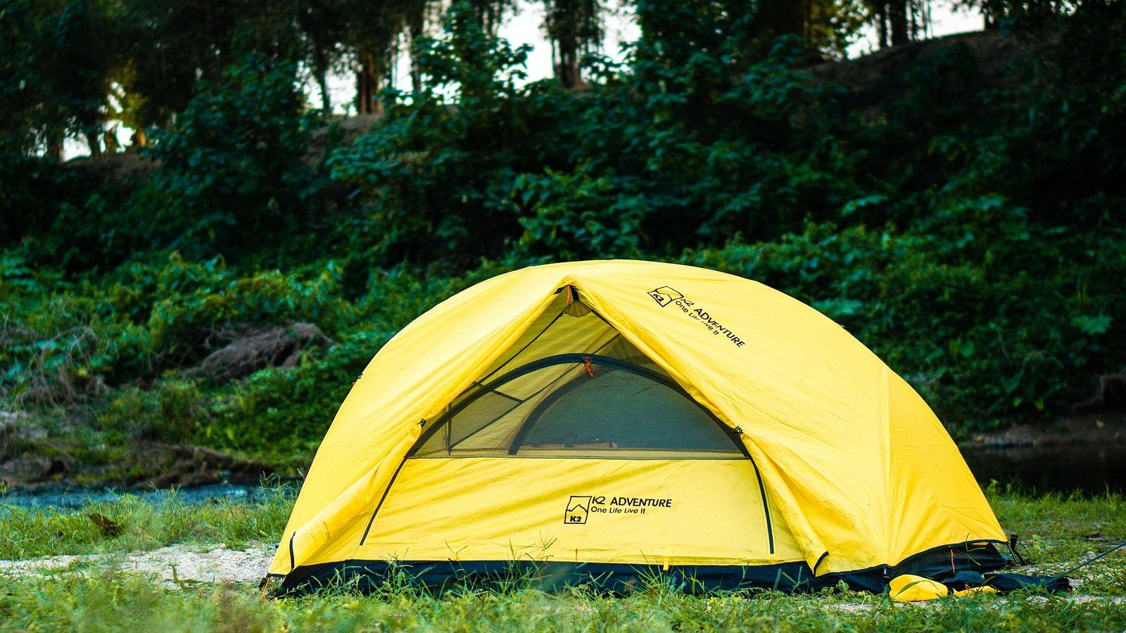 Blue tent on land surrounded by trees banner image