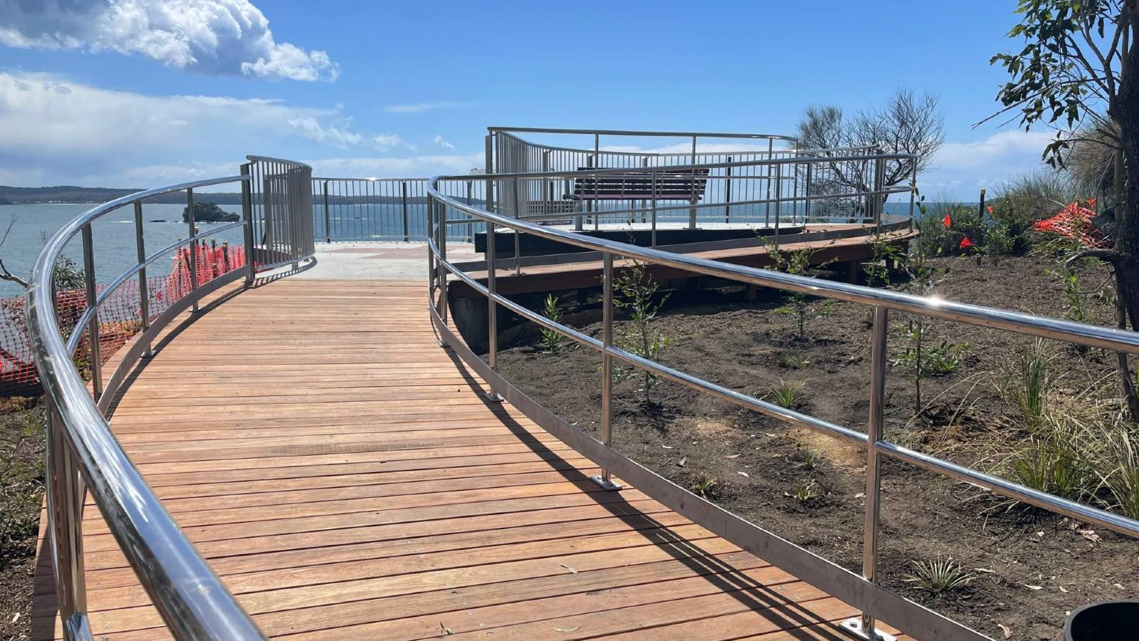 Image A curved timber ramp leads to a viewing platform overlooking the ocean.