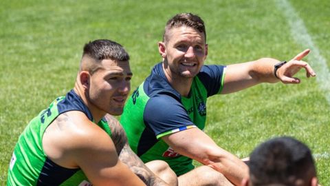 two fit men sitting on the grass wearing singlets