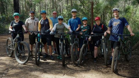 8 bike riders standing in  a line with bikes