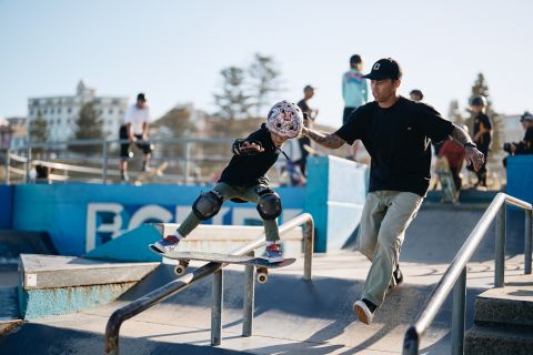 Man holding child while skateboarding a rail