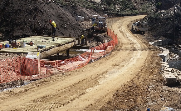 Image People work to build the new bridge alongside the temporary access track